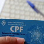 Pessoa segurando um cartão de CPF da Receita Federal, documento utilizado para identificação cadastral e regularização do CPF necessária para receber precatórios e RPV.