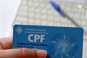 Pessoa segurando um cartão de CPF da Receita Federal, documento utilizado para identificação cadastral e regularização do CPF necessária para receber precatórios e RPV.