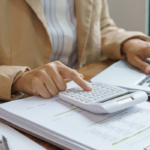 Pessoa usando calculadora e laptop para gerenciar precatório federal de servidor público